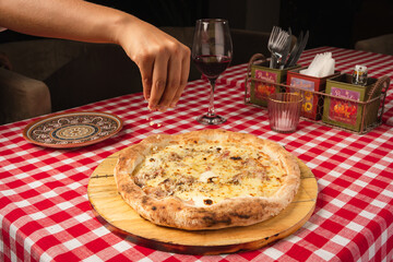 person adding cheese  at pizza