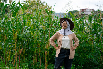 Young Asian female farmer who looks happy seeing her corn plants growing well. Young farmer woman...