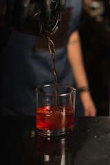 barman serving cocktail into glass
