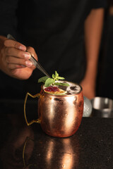 barman adding mint to a moscow mule