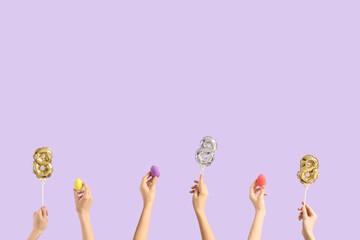 Female hands with balloons in shape of figure 8 and makeup sponges on lilac background. International Women's Day celebration