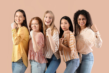 Beautiful young women with clenched fists on beige background. Women history month
