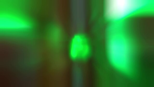 A bunch of neon green rays flicker on a dark background. Abstract blurred zoom background