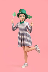 Funny girl with face painting, clovers and leprechaun's hat on pink background. St. Patrick's Day celebration