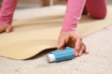 Sporty young woman taking asthma inhaler from floor at home, closeup - obrazy, fototapety, plakaty