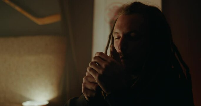 Rasta man lighting up his spliff in a smoke filled cozy chill room