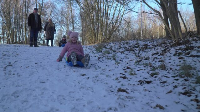 Kids bobsledding down hill with grand parents watching