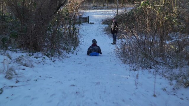 Kid bobsledding down hill with grand parents watching