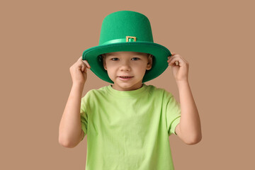 Cute little boy in leprechaun hat on brown background. St. Patrick's Day celebration