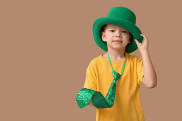 Cute little boy in leprechaun hat on brown background. St. Patrick's Day celebration