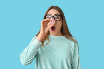 Beautiful young shocked woman in funny disguise on blue background. April Fools Day celebration