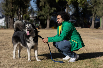 Young man with curly hair in Mexico City park with his husky dog