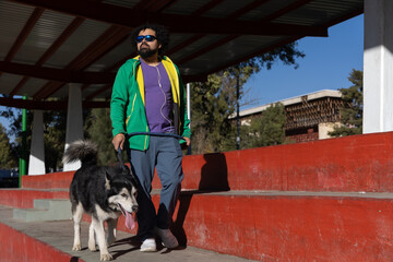 Young Mexican man walking with his husky in a city park