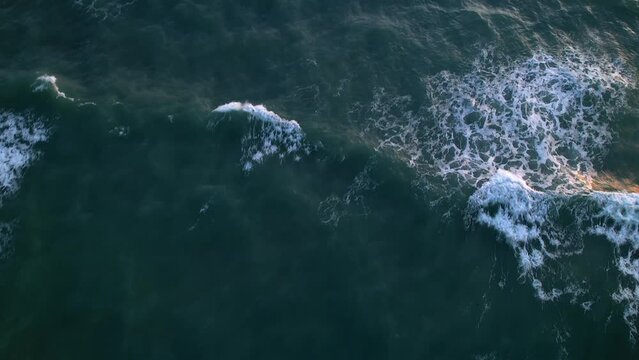 ocean waves roll and break in sunset as drone follows above slight rotation asmr