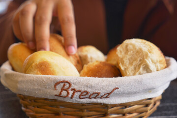 women hand pick baked bun on table 