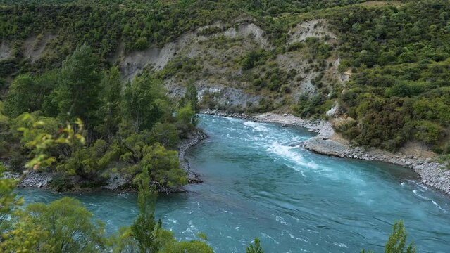 Kawaraw river flows between mountains at Roaring Meg, Queenstown, New Zealand, pan shot, camera movement