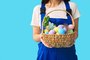 Female worker with Easter eggs on blue background, closeup