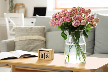 Calendar with date of International Women's Day and roses on table in living room, closeup