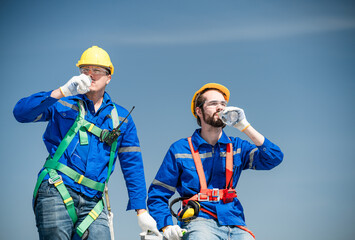 Male technician holding solar panels on factory roof An engineer in a helmet takes a drink break before installing an outdoor solar panel system. solar cell storage