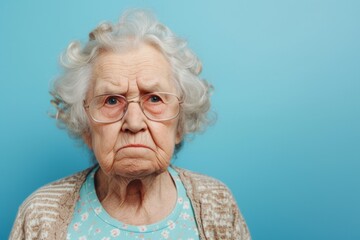 Grumpy Elderly Lady on a Solid Blue Background. Generative AI. - obrazy, fototapety, plakaty