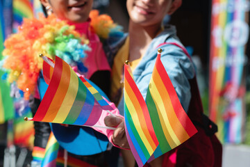 Two gay men join in the fun at the Pride parade, showing and waving flags in celebration of Pride Month, LGBTQ concept, selective focus