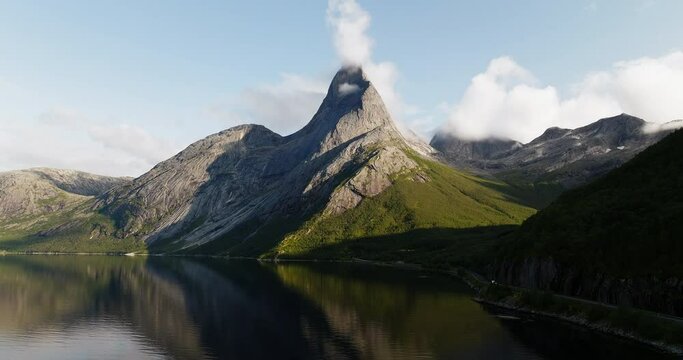 Curved mountain bares to grey peak with clouds gathered at top, Stetind Norway