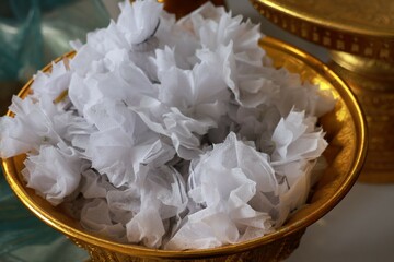 Wrap a white cloth and put coins in it for scattering at merit-making events.