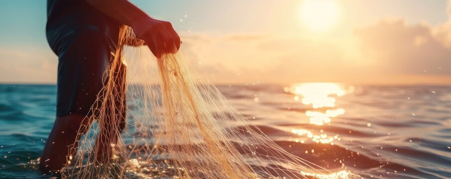 Spreading fishing net silhouette with gold twilight sea sky in background
