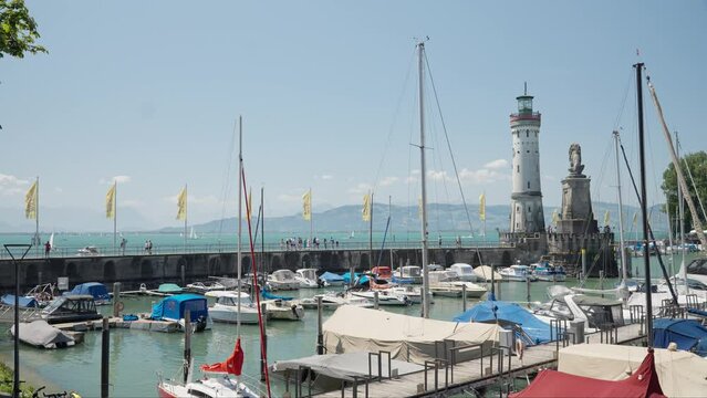 Sunny day at Lindau Harbor with boats, lighthouse, and statues, clear blue sky