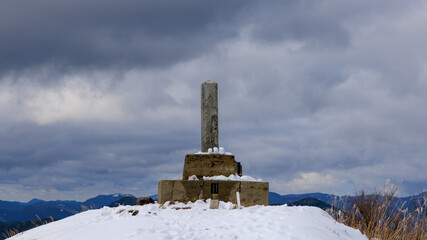 Stone concrete marker on summit of snowy mountain on cloudy day - 728966618
