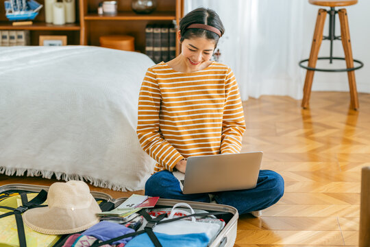 旅行の準備をしながらウェブで予約する若い女性