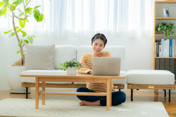 リビングでくつろぎながらパソコンを見る若い日本人女性
