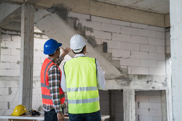 Civil engineer with personal safety equipment checking and consult with construction site foreman...