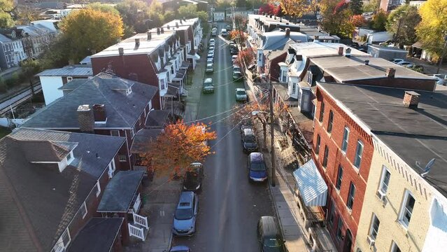 Urban housing in American city during autumn. Aerial establishing shot above old rowhouses during sunset.