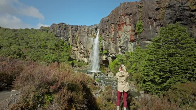 Lone female photographer taking pictures of beautiful Taranaki waterfall