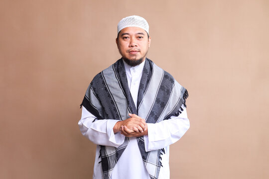 Portrait of bearded Asian muslim man  in white robe and cap