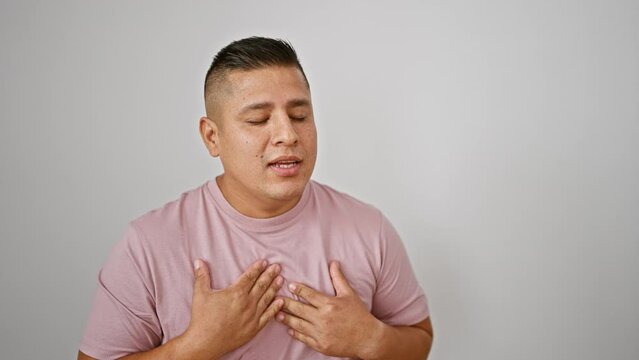 Young handsome latin man standing isolated, seriously coughing up a storm over white background, cold or covid-19?