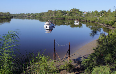 Boyne River with boats anchored in the water surrounded by trees at Boyne Island, Queensland,...