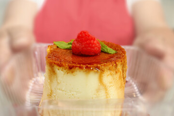 A chef holding a flan a custard dessert with a layer of clear caramel sauce.
