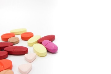 Detailed photos of oval, round and triangular shaped tablets in various colors: red, orange, yellow and cream. The photo was taken on a white background