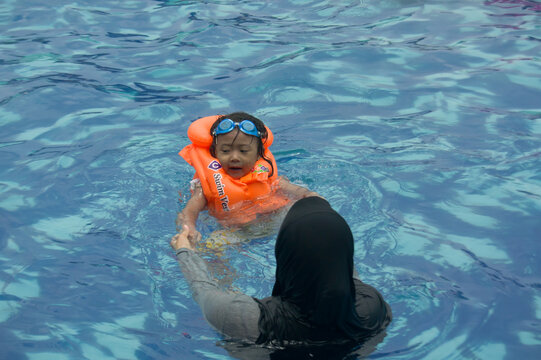 A mother teaches her daughter how to swim - Powered by Adobe