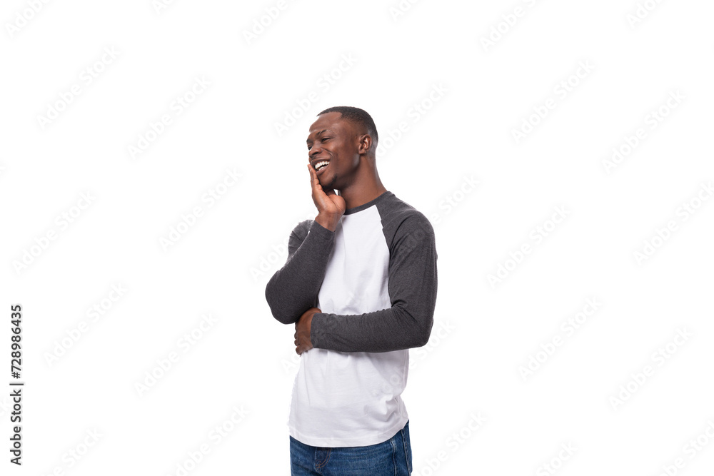 Wall mural young happy african guy dressed in a sweatshirt feels joy