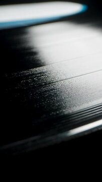 Close-up reveals a spiral groove on the vinyl record, a sound track on a black background.