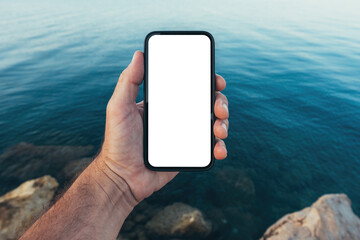 Smartphone screen mockup, man holding mobile phone with blank white touchscreen above blue ocean...