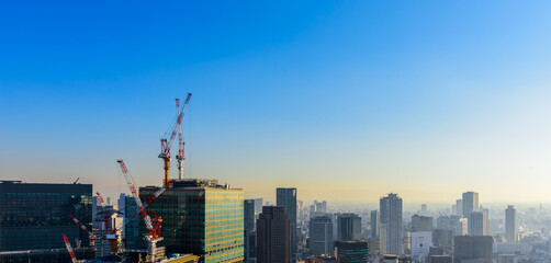 Panorama city skyline, tower cranes and unfinished buildings, construction cranes on blue sky with city skyscrapers background at construction site.