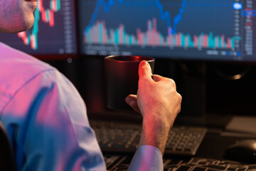 Cropped working young business trader holding coffee cup with focusing on market stock graph data...
