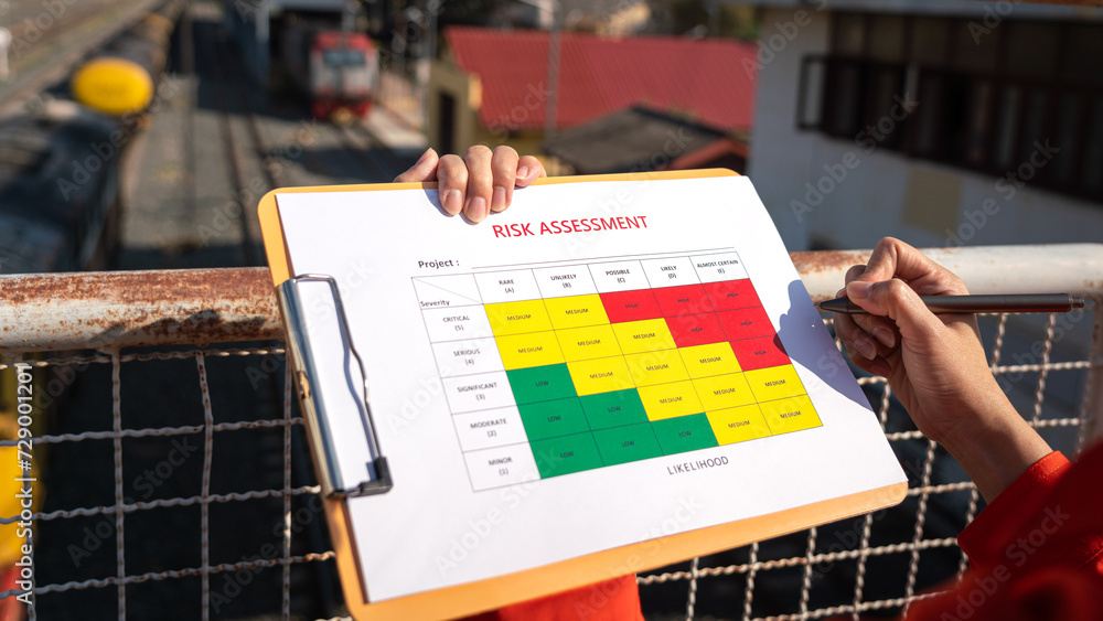 Wall mural action of a business manager is holding project risk assessment form on blurred background of train 