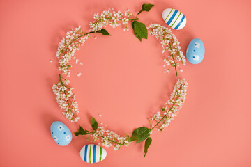 Easter eggs and cherry branches in the shape of a circle on a pink background. Copy space. Easter background, top view