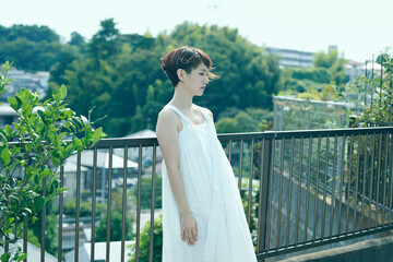 緑のある庭に佇む白いワンピースを着たショートヘアの女性