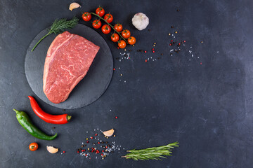 Raw fresh marbled meat and seasonings on dark background top view